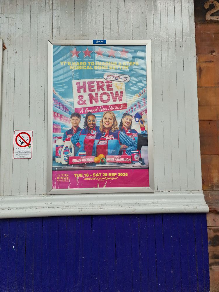 Poster for a new musical themed in pink and blue. Title: Here and Now: A Brand New Musical". Image shoes four young people smiling behind what appears to be a stylised supermarket checkout. Review from The Stage reads: "It's hard to imagine a Steps musical done better". In fairness, there are 5 pink stars above the review.