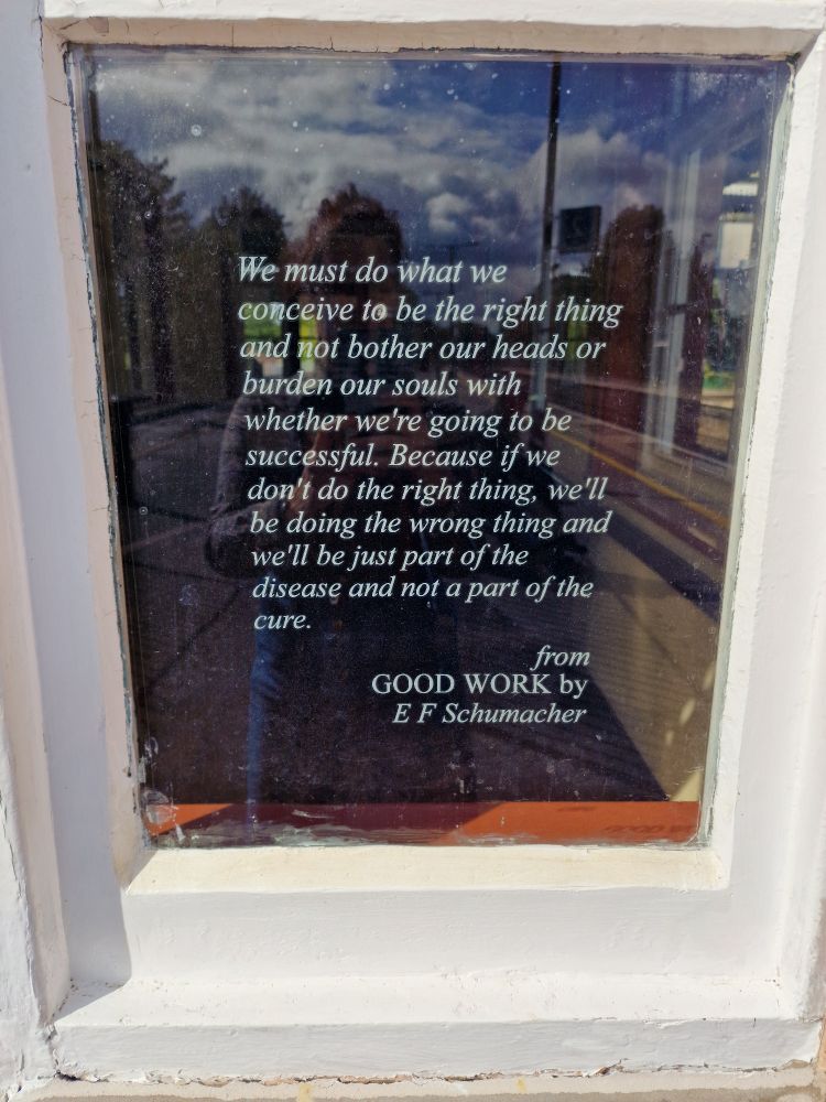 Text written in white on a small window panel bordered with white-painted stone: "We must do what we conceive to be the right thing and not bother our heads or burden our souls with whether we're going to be successful. Because if we don't do the right thing, we'll be doing the wrong thing and we'll be just part of the disease and not a part of the cure. - from GOOD WORK by E.F. Schumacher."