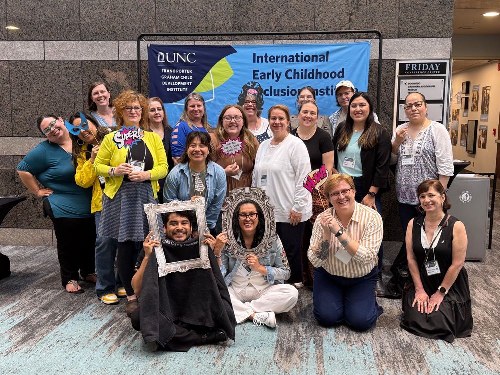 A group of attendees pose in front of an Inclusion Institute banner.