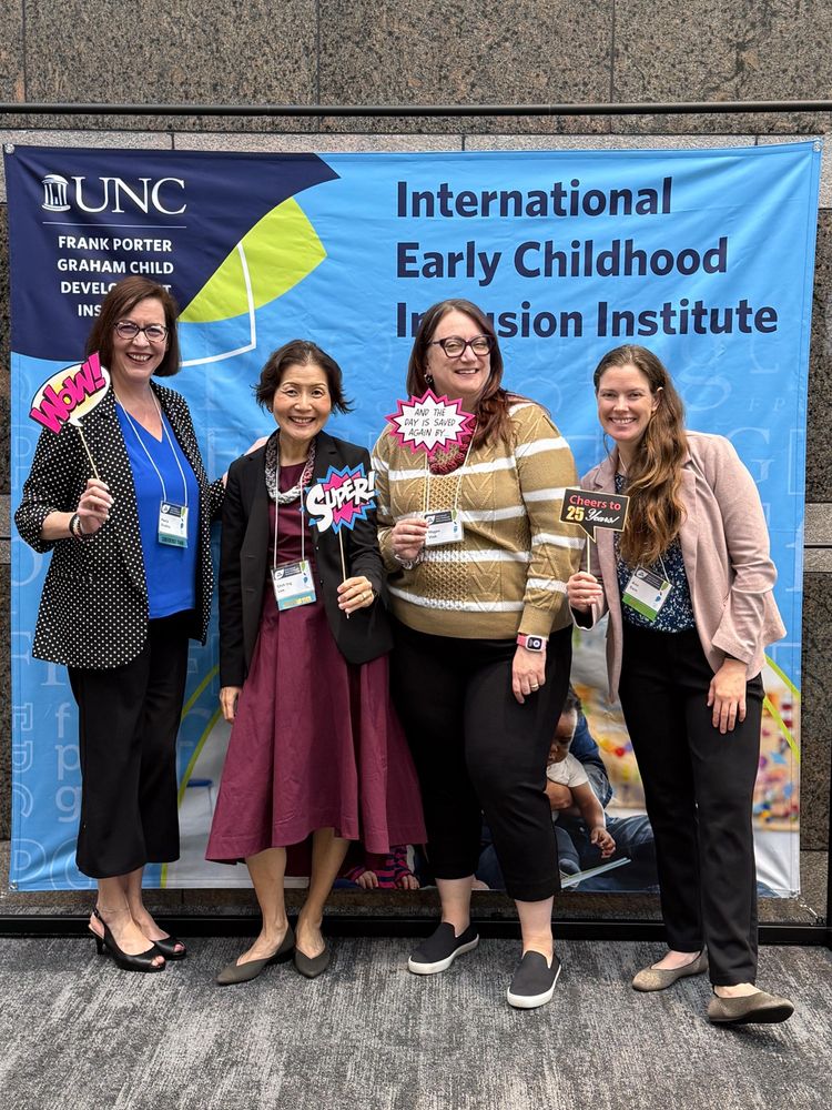 Inclusion Institute co-chairs and volunteers pose in front of a conference banner.
