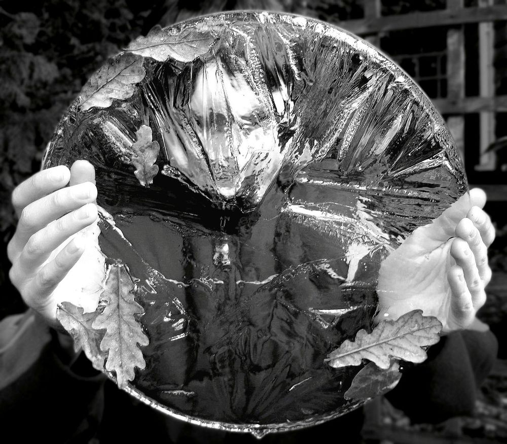 young person holding circular sheet of ice in front of their face which distorts the image