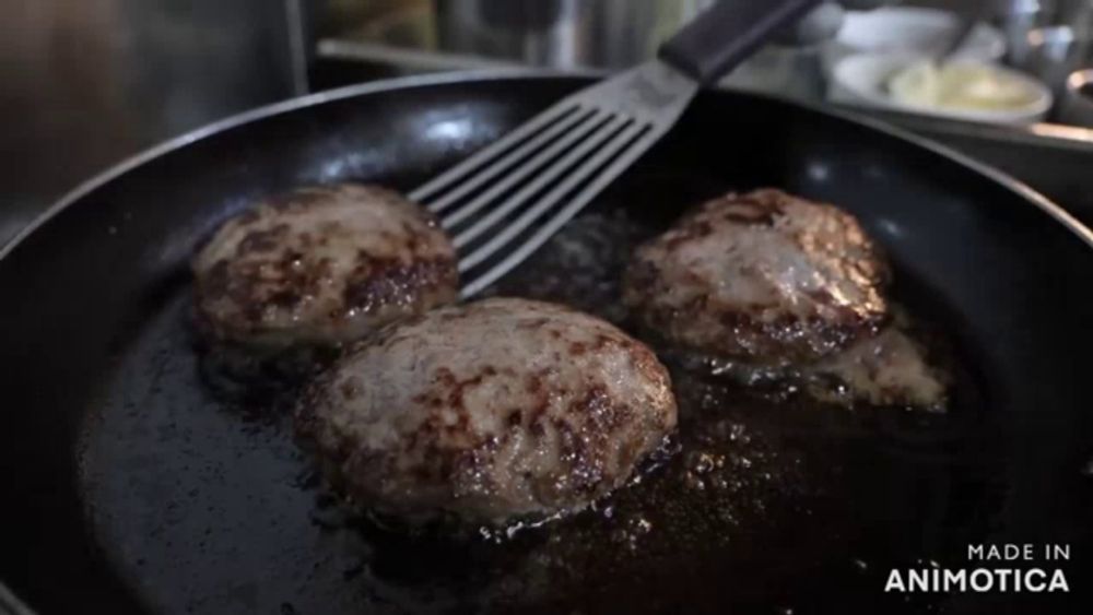 three hamburger patties are being cooked in a frying pan and the words made in animotica can be seen in the corner