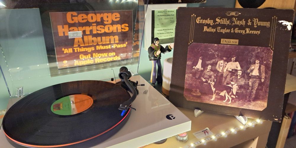 Deja Vu by CSNY. The picture shows the album sleeve adjacent to the turntable spinning the disc.  