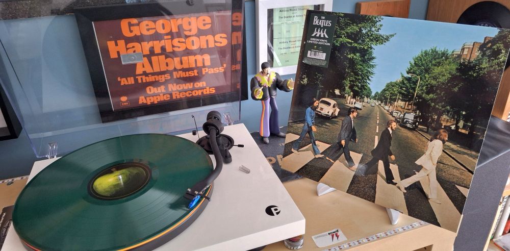 The new green vinyl pressing of Abbey Road by the Beatles,  adjacent to the turntable spinning the disc. 