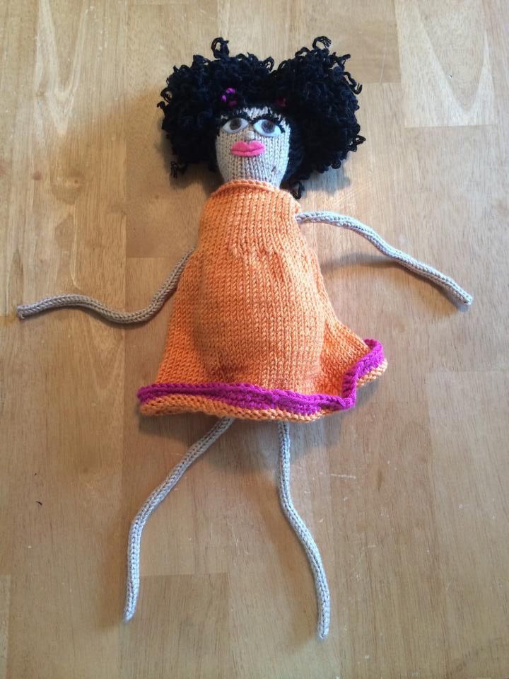 Knitted doll with an orange dress and black hair. 