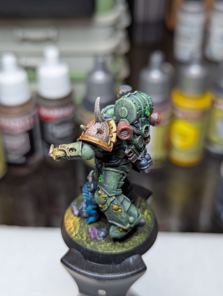 A Death Guard Plague Marine, readying to toss a grenade as a nurgling grasps pleadingly for the pin.
