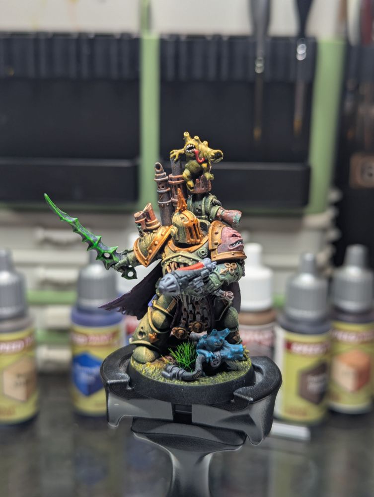 A Death Guard Champion wielding a sword and plasma pistol, clad in green power armor and joined in battle by 2 nurglings