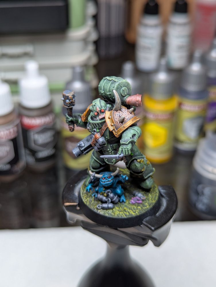 A Death Guard Plague Marine, readying to toss a grenade as a nurgling grasps pleadingly for the pin.
