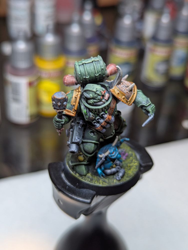 A Death Guard Plague Marine, readying to toss a grenade as a nurgling grasps pleadingly for the pin.