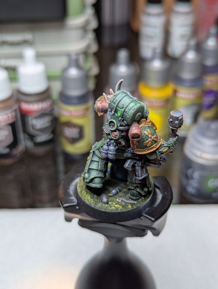 A Death Guard Plague Marine, readying to toss a grenade as a nurgling grasps pleadingly for the pin.