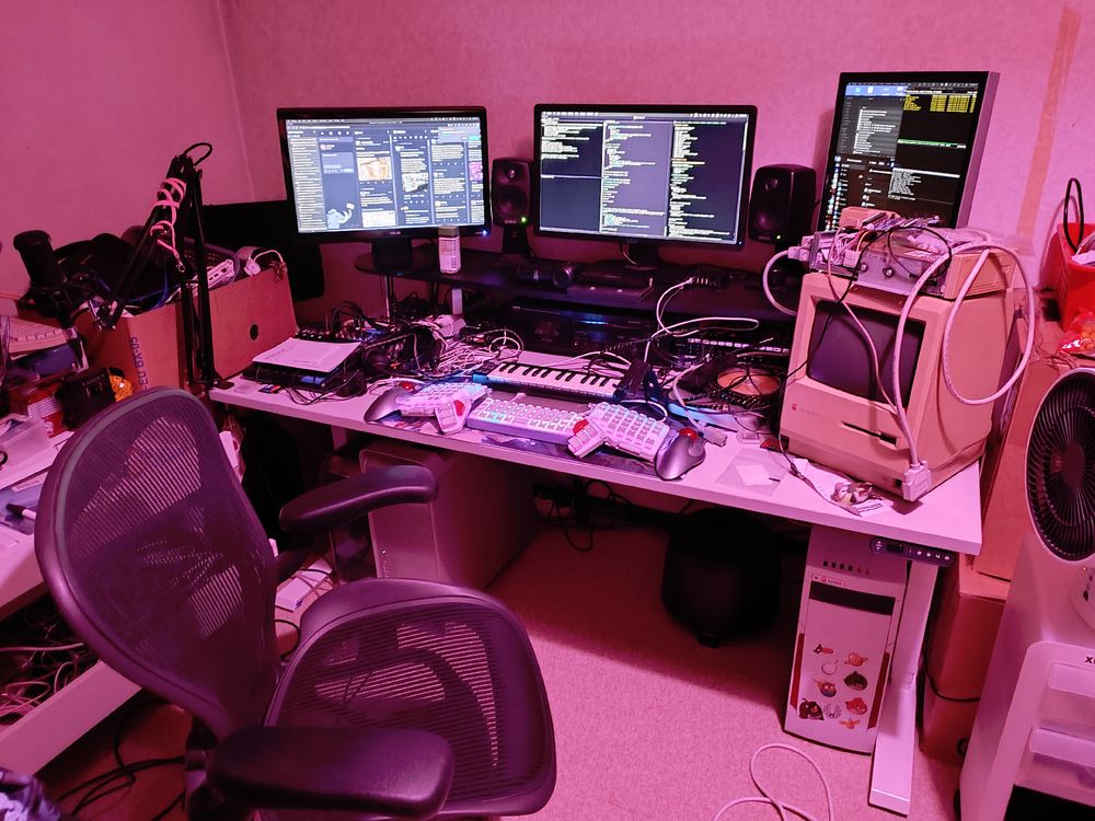 computer desk with three desktops underneath three displays on top and various other devices