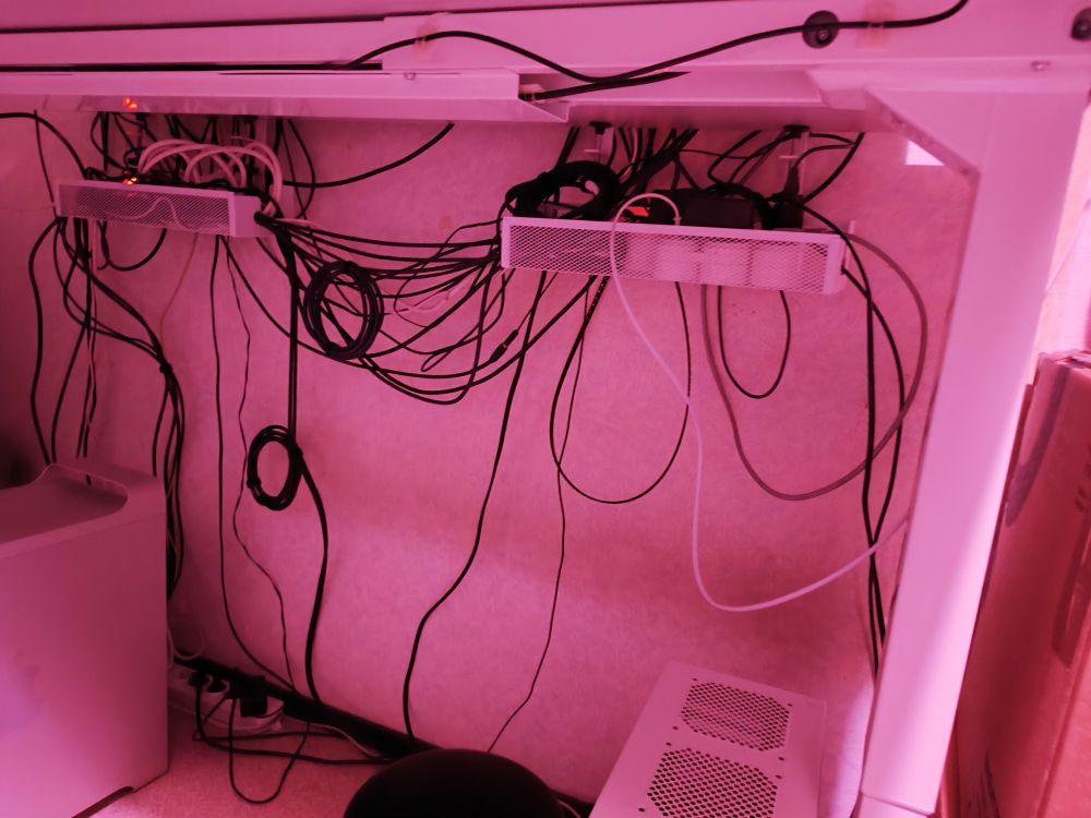 cables under the desk. many are running through trays suspended from the desk. some are tied together with velcro bands