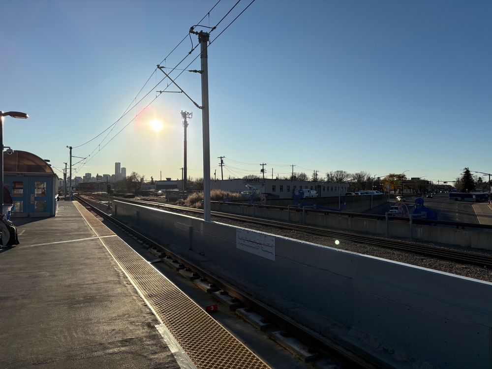 A view from a train station platform showing the sun is low in the sky