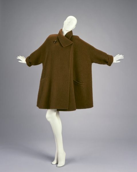 mannequin in a brown coat, arms flung to the side in rapture