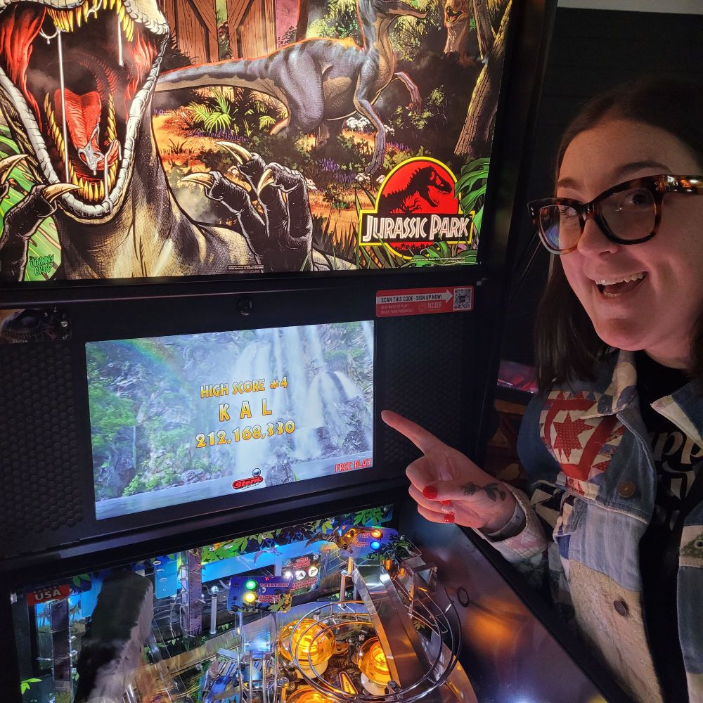 Katie pointing at her ranking score on Jurassic Park pinball