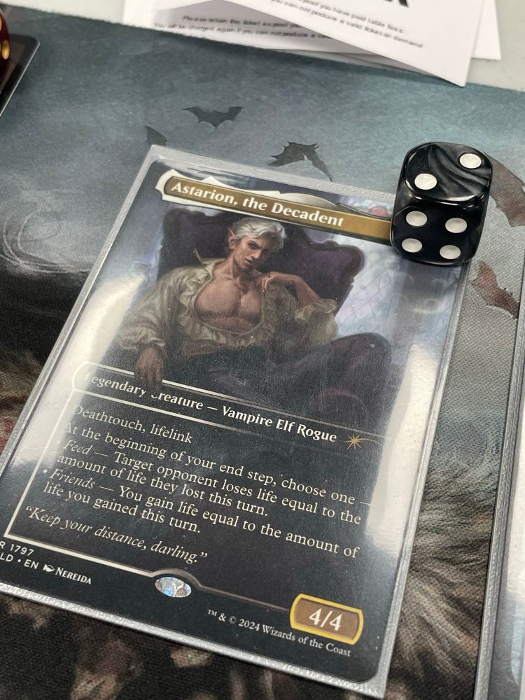 Astarion the Decadent (secret lair version) in silver sleeve with dice counter, on playmat 