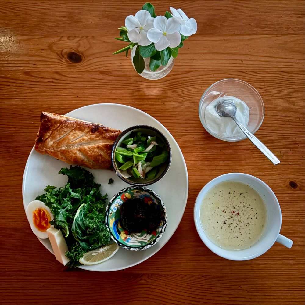 朝食　白丸皿にカスタードアップルパイ ゆで卵 ゴーダチーズ ケール レモン 小鉢のもずく・小松菜しめじおひたしが載っている　コーンポタージュ　低脂肪乳ヨーグルト