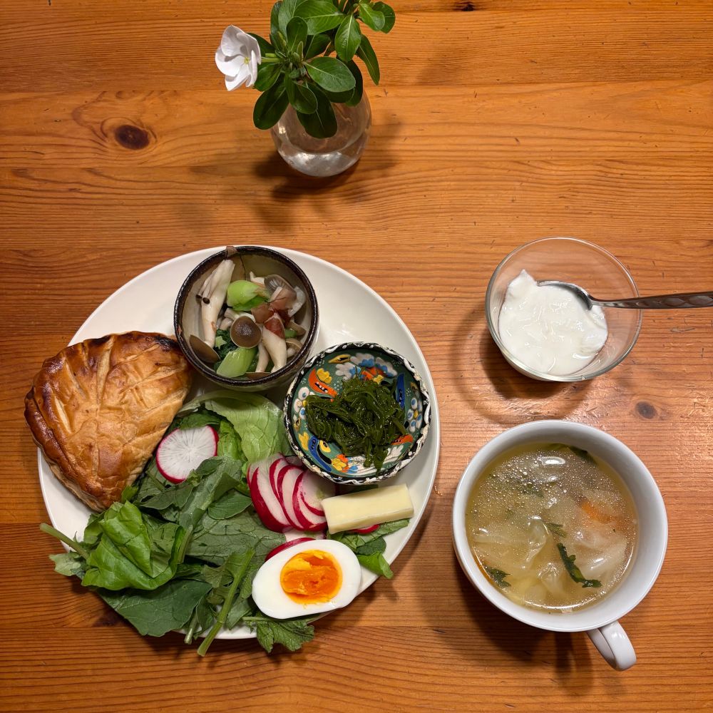 朝食　白丸皿にアップルパイ サラダ ゆで卵 ゴーダチーズ 小鉢のめかぶ・青梗菜しめじおひたしが載っている　野菜スープ　低脂肪乳ヨーグルト