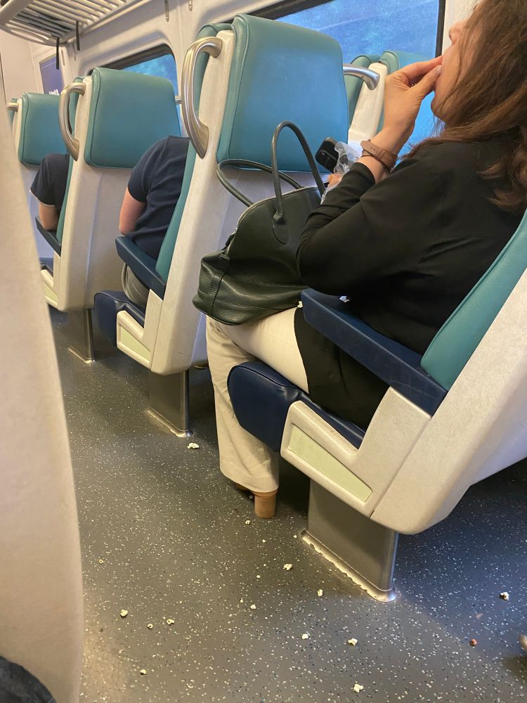 Just an absolutely filthy mess of popcorn on the floor of a train from a lady who does not for one single second believe that she should care about anybody else in the world. 