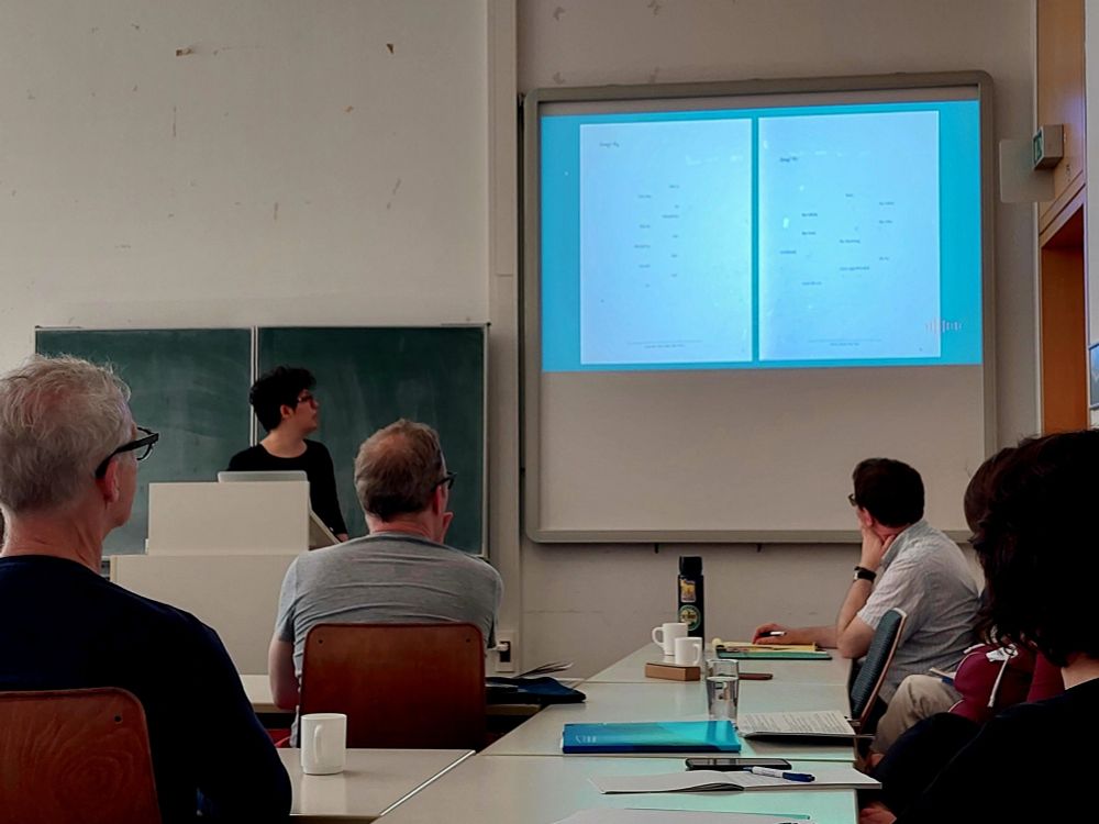 Scene from a conference room: the presenter is showing a formally experimental poem consisting of words displayed on a page with a lot of spacing.