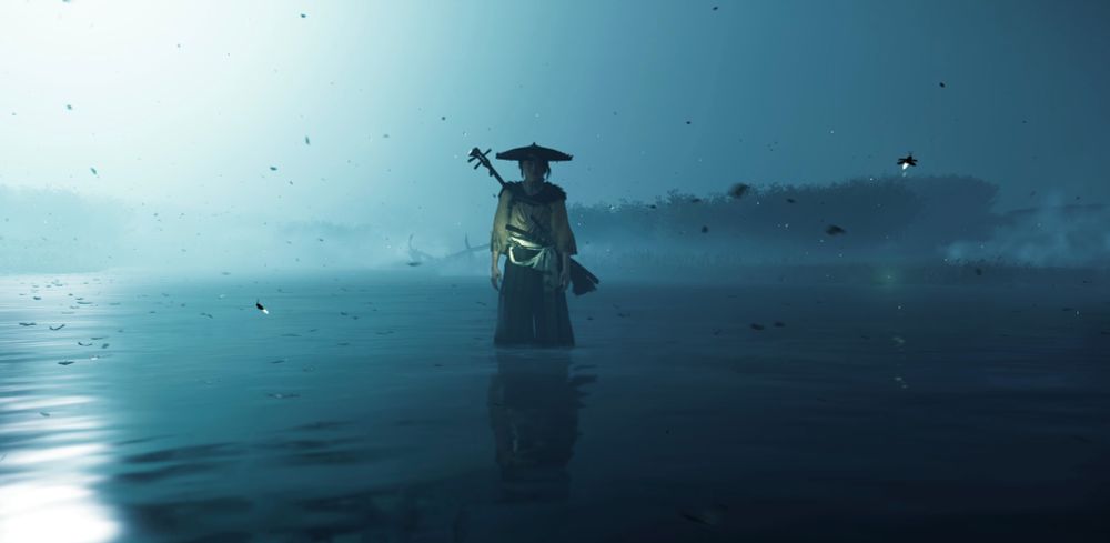 Atsu stands in a river by night.
