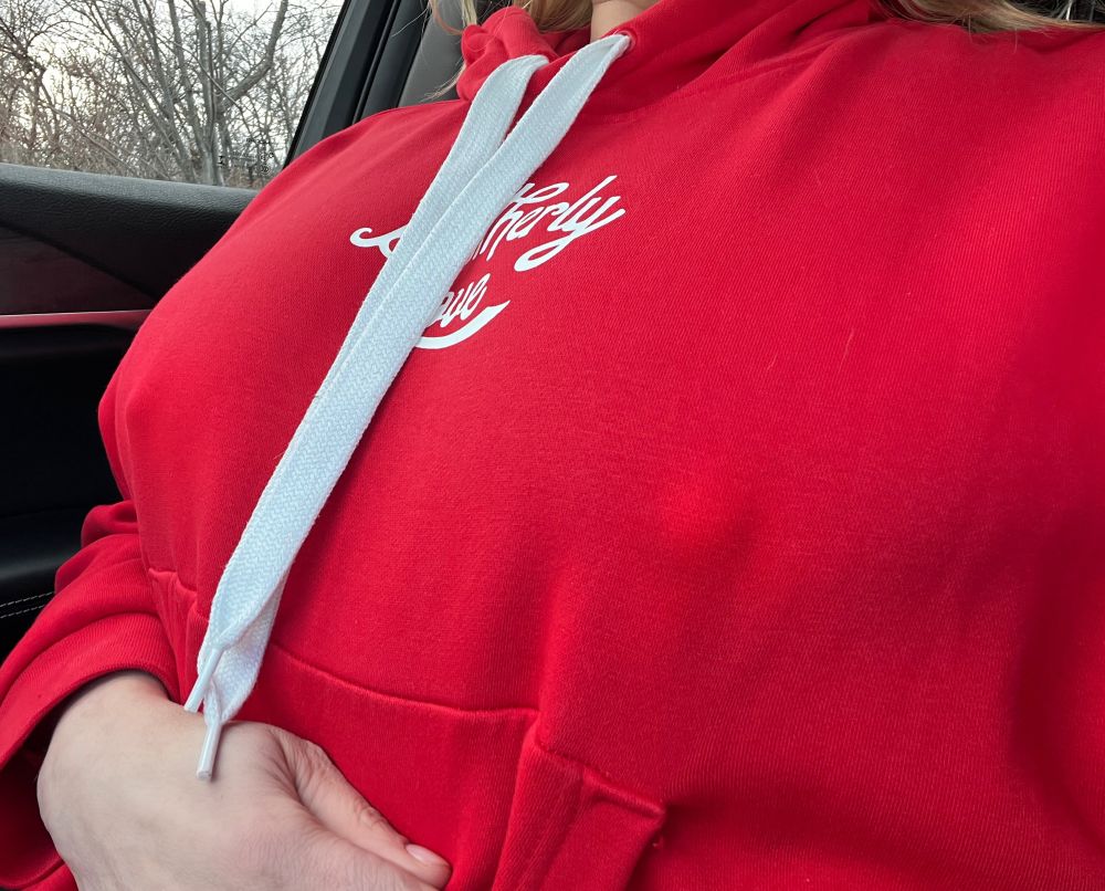 Fansly content creator wearing a thick red sweatshirt with thick hard nipples poking the fabric. 