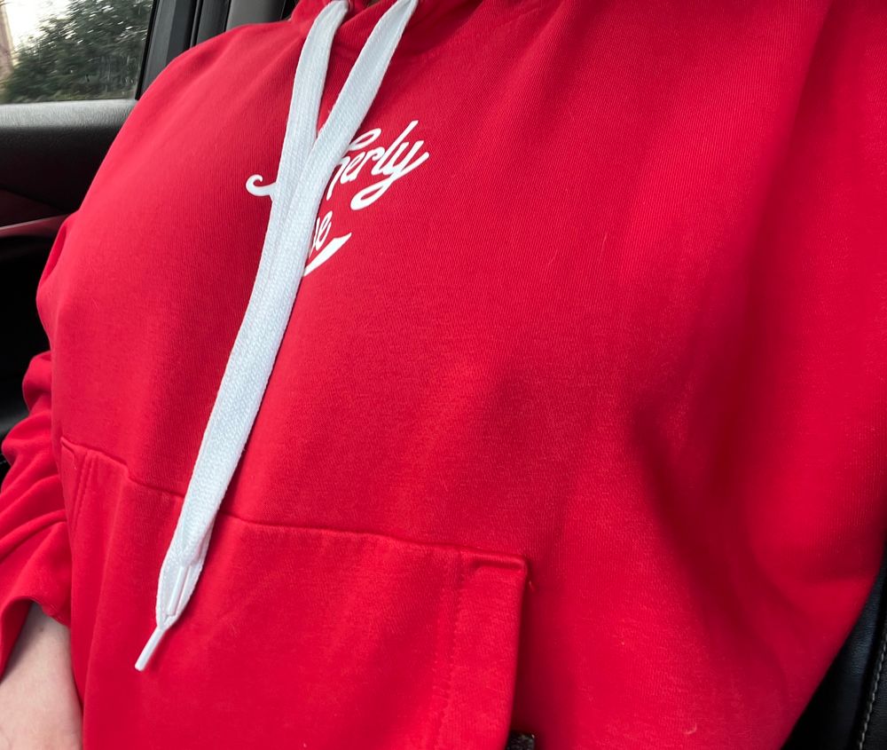 Fansly content creator wearing a thick red sweatshirt with thick hard nipples poking the fabric. 