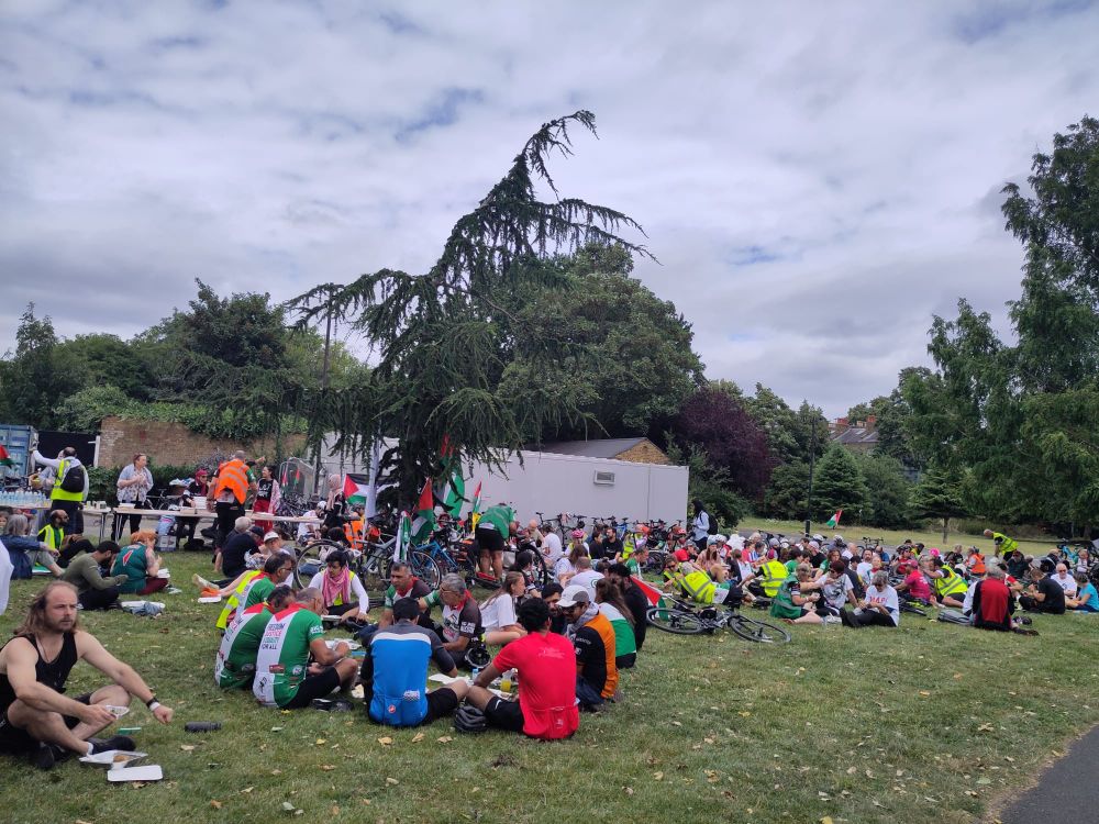 Big Ride For Palestine cyclists on their lunch break, sitting on the grass in a London park