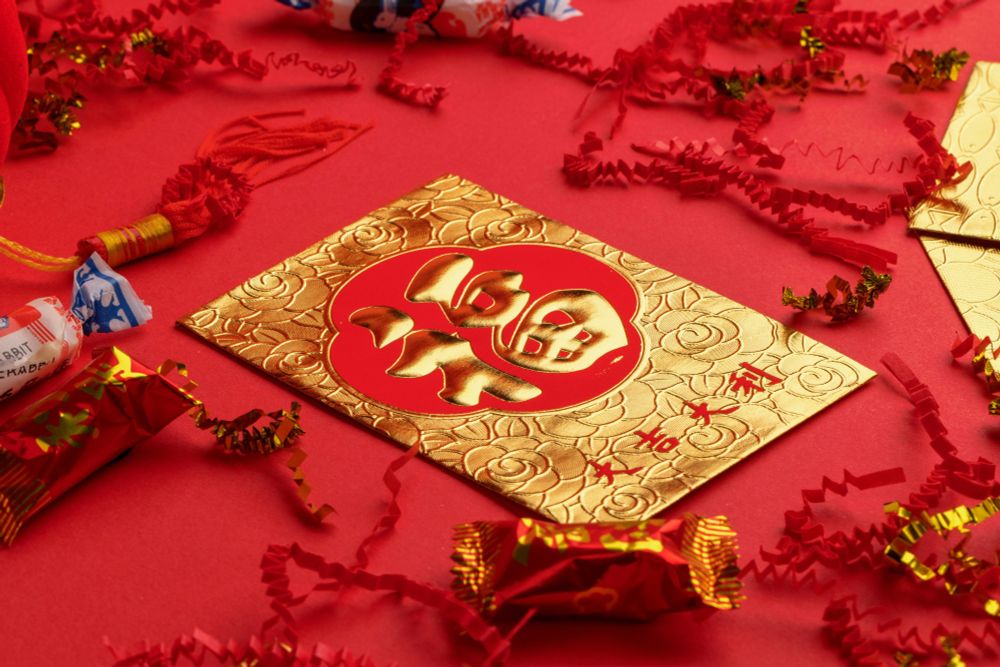 Gold and red lucky money envelope surrounded by lunar new year candy and decorations