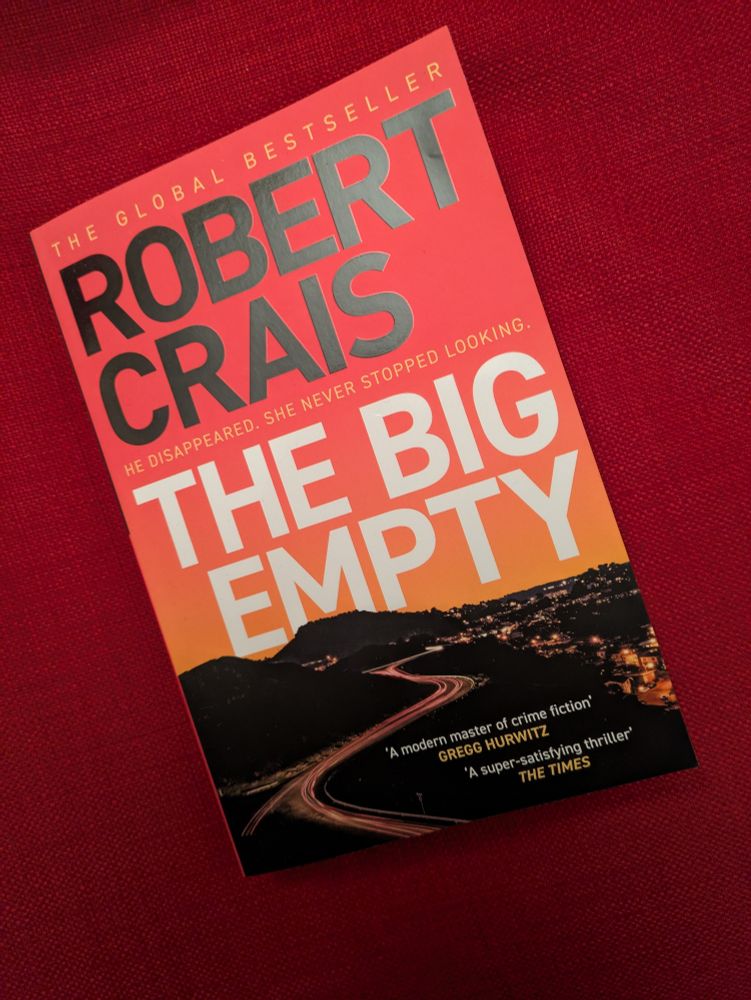 Cover of The Big Empty by Robert Crais - the name and title against a red sunset sky above a lonely road with city lights in the distance. 