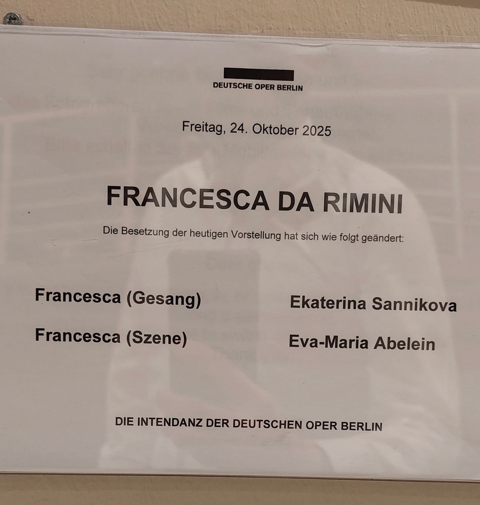 Ein Aushang, auf dem eine Besetzungsänderung angekündigt wird. Schemenhaft sieht man einen Mann im weißen Hemd, der sich spiegelt.