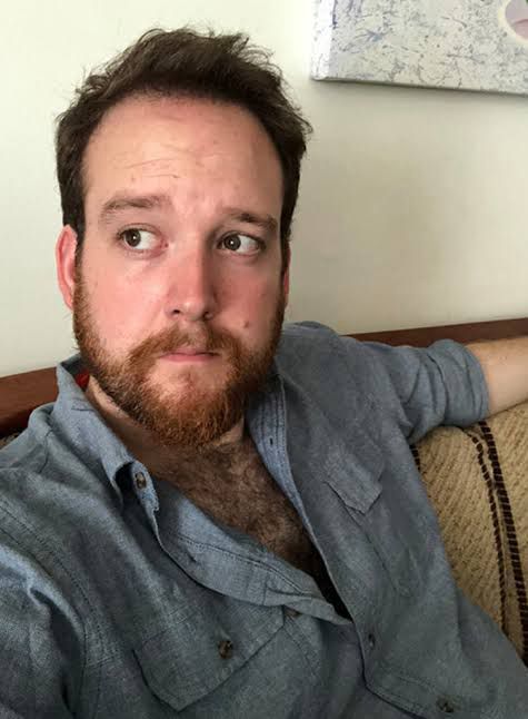 A photo of Harlan Guthrie, sitting on what looks to be a couch and staring thoughtfully out of frame