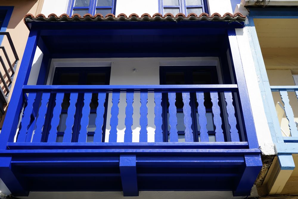 Casa cun balcón pintado de azúl e a fachada en branco.