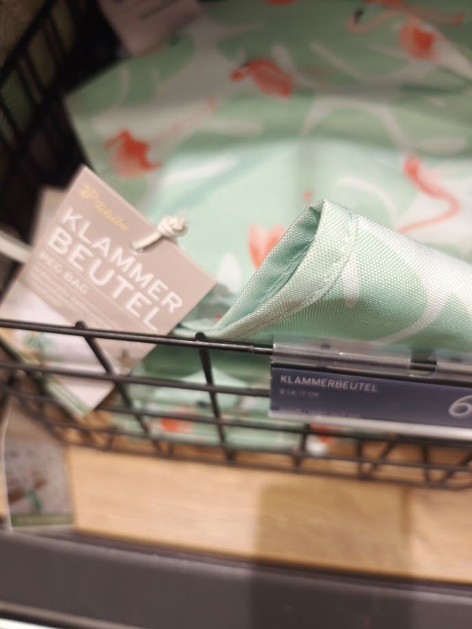 Warenauslage, Körbchen mit lindgrünen Klammerbeutel, das Wort steht auf den Produktschildern, man sieht die Ziffer des Preises