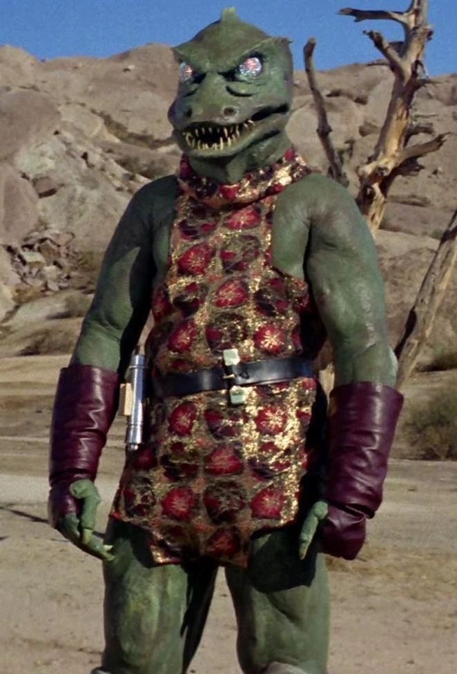 Classic Star Trek character Gorn, a green lizard man wearing gauntlets and and a tunic. he is standing in the desert. He is ready to fight for his right to party.
