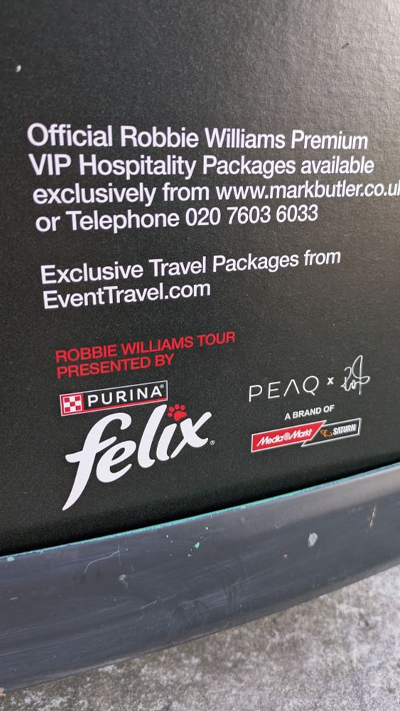 Foto von einem Tourplakat des Künstlers Robbie Williams. Zu lesen ist u.a.: „Robbie Williams Tour presented by Felix, Purina, MediaMarkt, Saturn“