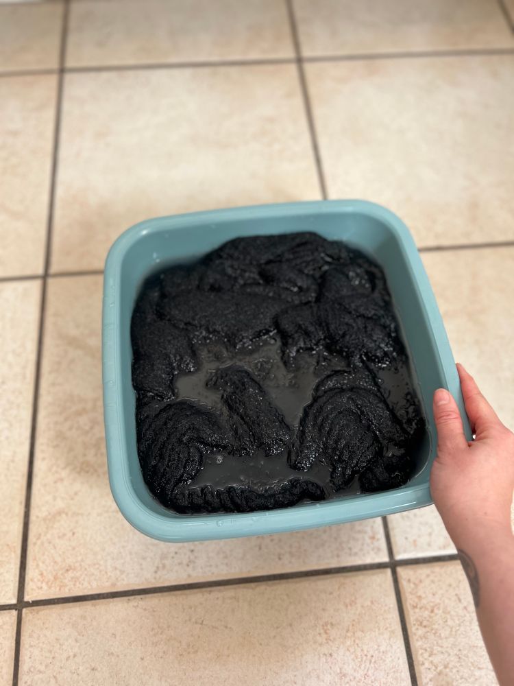 Small bucket of soapy water with the new sweater soaking in it.