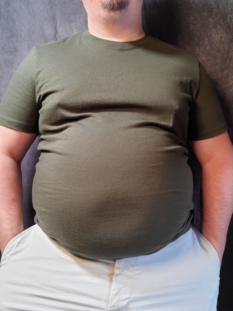 Babyblueboxers standing in a green shirt and khaki shorts. Belly is round. 