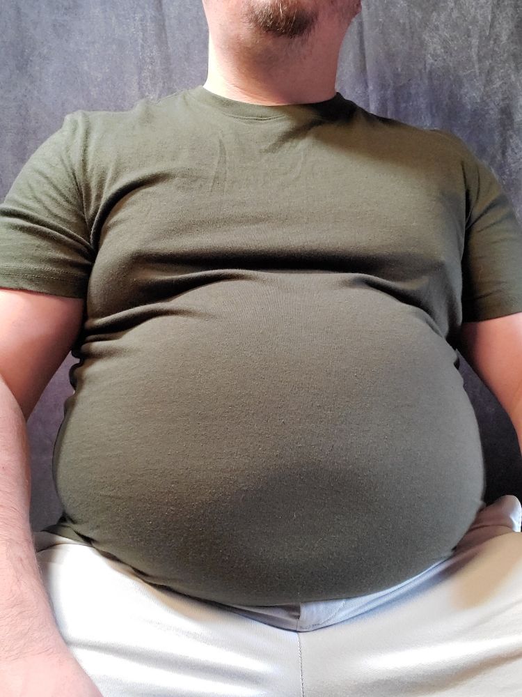 Babyblueboxers sitting in a green shirt and khaki shorts. Belly is round. 