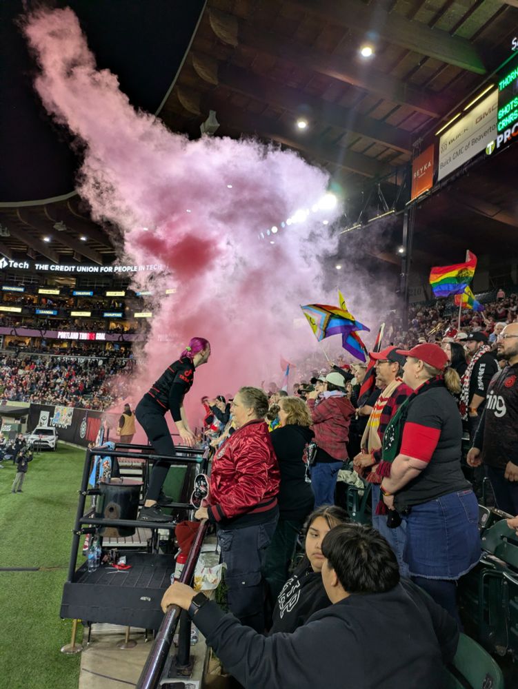 A red smoke flare goes off on front of a grandstand of cheering Portland Thorns fans at the stadium