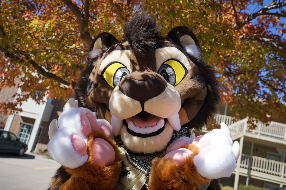 Miles poses with a smile in front of the fall leaves and trees