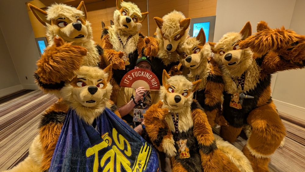 Me surrounded by the Pack o Nines suiters while I hold up a folding fan that says "it's fucking hot"