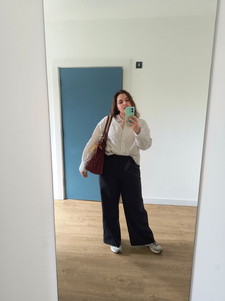 Mirror selfie, a blue door in the background, beige floor and white walls, in the centre me in black trousers, sneakers, a white shirt. 