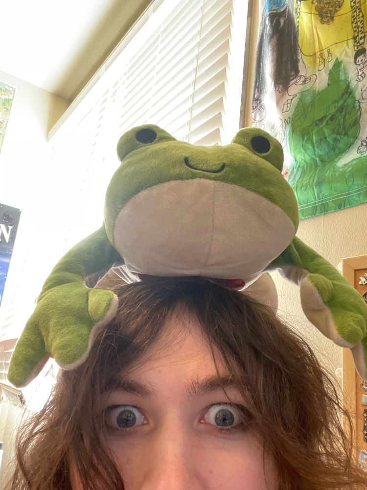 Ted the Dissectible Frog sitting on top of Natalie Fae’s head, she is staring intently into the camera