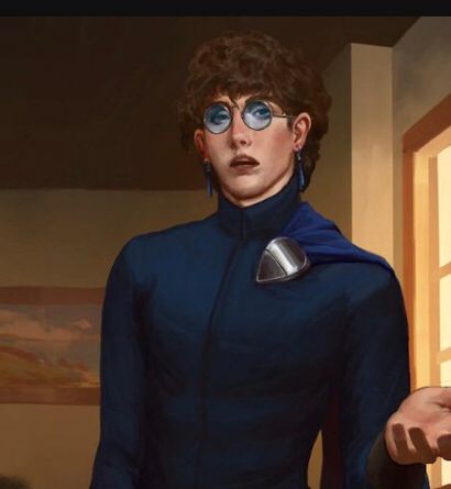 Clean-shaven man with pale skin and curly dark hair stands with one hand out. He wears tinted glasses that are perfectly round, blue tassel earrings and a cape on one shoulder. 