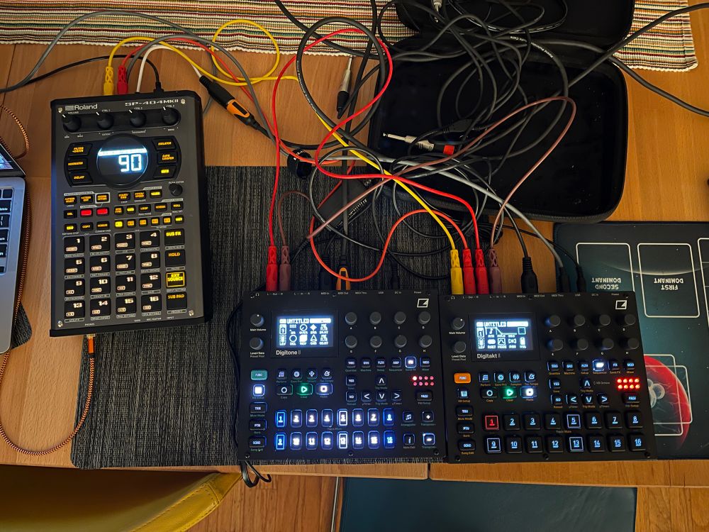 A table full of music boxes connected by a mess of cables 
