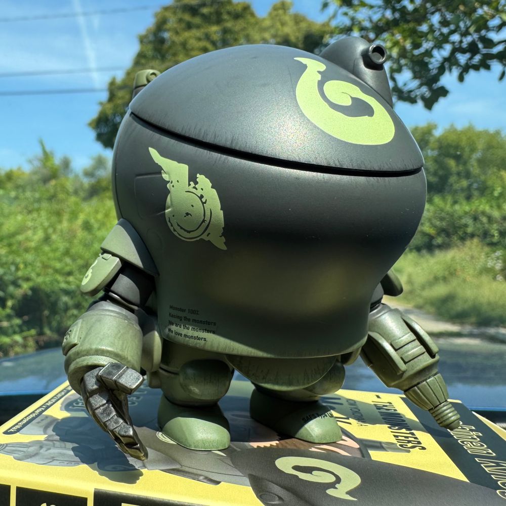 Another image of the figurine featured on the front of the box. It looks like military grade robotic power armor but the body is cute and round. Almost like a cooking pot with robotic arms and legs. 