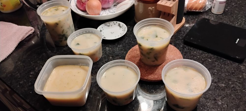 various deli containers of cream soup on a kitchen counter. 