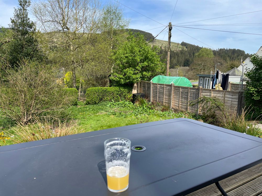 Beer, garden table, sunny and green Scottish landscape. 