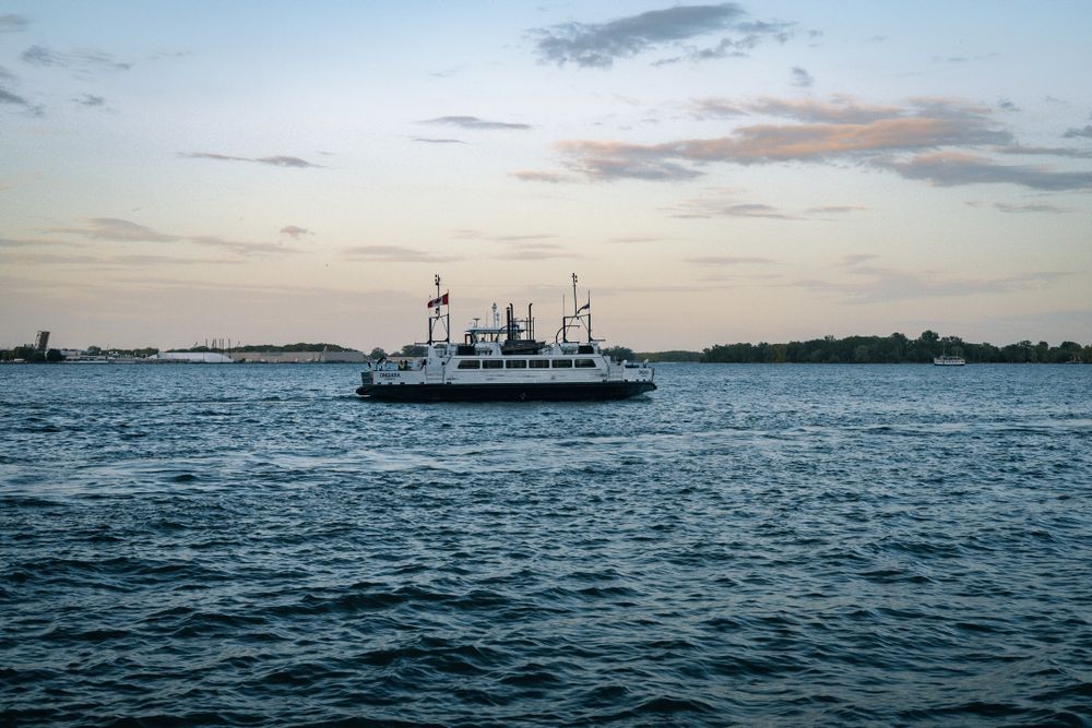 A Toronto ferry cruises on a body of water at dusk. 